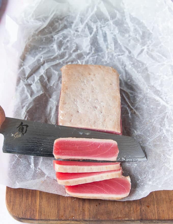 A sharp knife used to slice the tuna showing the beautiful pink raw inside of the ahi tuna 