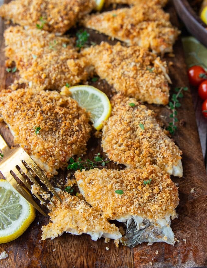 A fork flaking a cooked perch recipe showing the flakey texture and perfectly cooked fish 