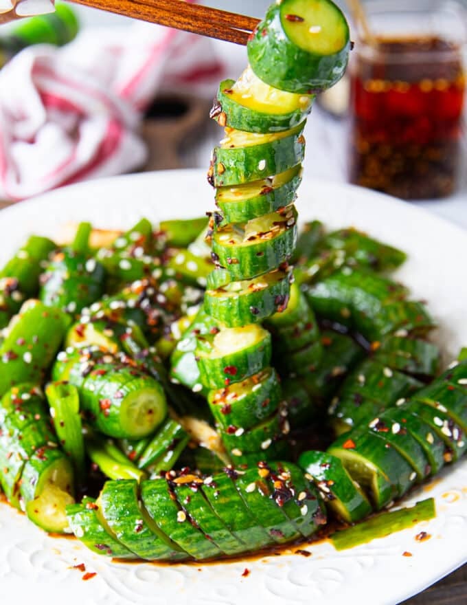 A chopstick stretching out a cucumber showing the twists and perfect dressing that's stuck all over the cucumber.