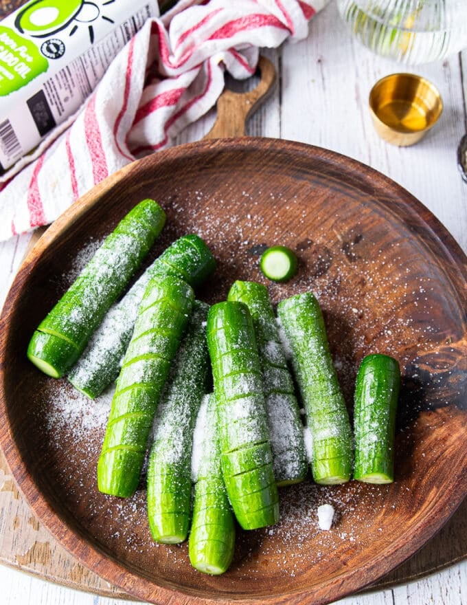 Salt added to the cut up cucumbers in a large bowl 