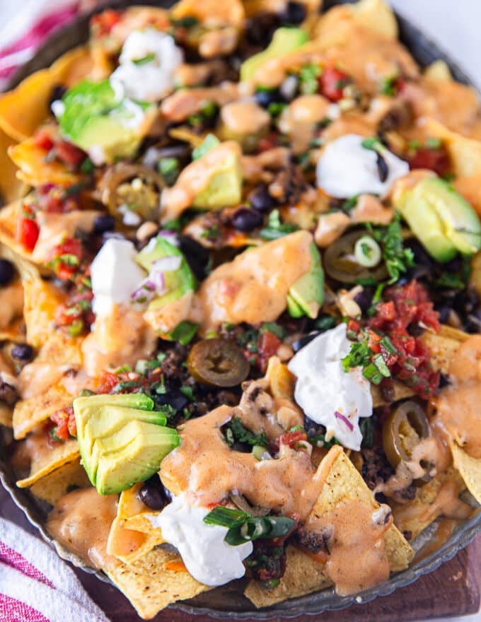 close up of the loaded nachos with cheese sauce and avocados, ready to serve