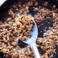 ground beef cooking in a cast iron skillet with onions, garlic, and homemade taco seasoning