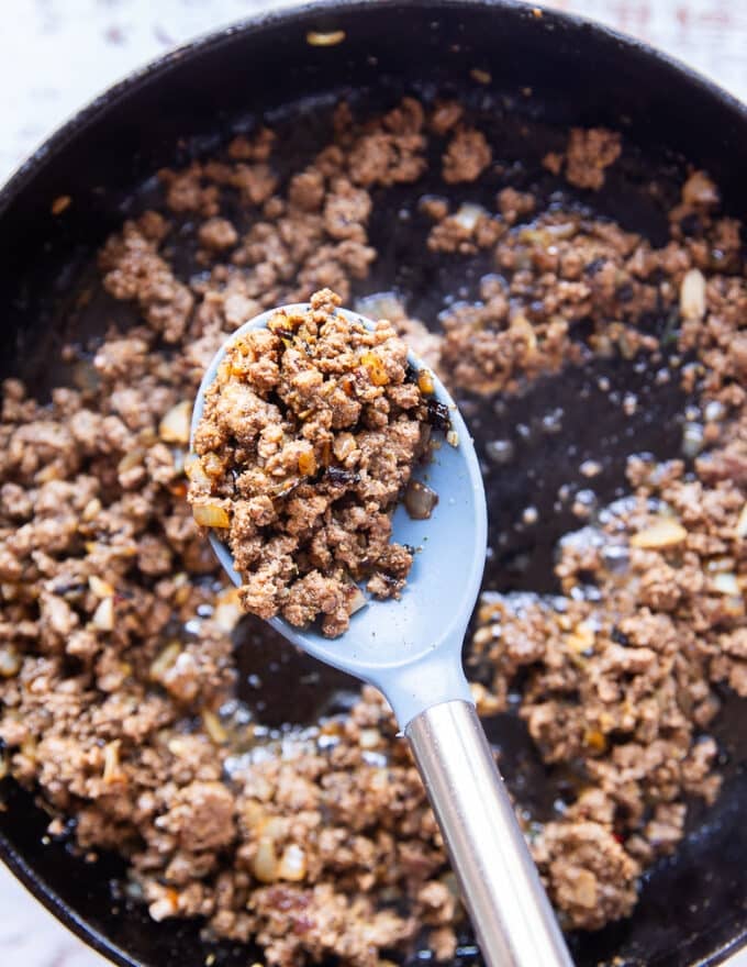 ground beef cooking in a cast iron skillet with onions, garlic, and homemade taco seasoning 