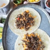 In a baking sheet, some soft tortillas are also layered with cheese and ground beef to show how you can make tacos with soft shells