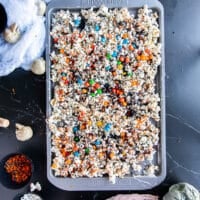 The tray of halloween popcorn sprinkled with spooky candies, black sprinkles, eyeball candies and more, ready to set