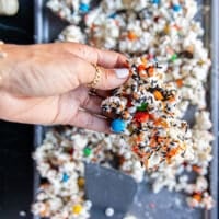 A hand holding a chunk of the halloween popcorn after it has set and all the spooky candy is showing