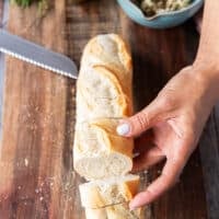 hand scorching the baguette into half inch slices not cuttiing all the way through and showing how to cut the bread