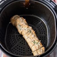 The garlic bread all slathered in butter and placed in the air fryer basket
