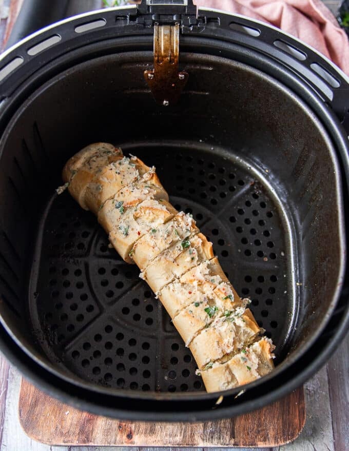 The garlic bread all slathered in butter and placed in the air fryer basket 