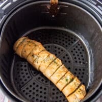 Slightly golden garlic bread in the air fryer basked ready and cooked in the air fryer