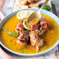 A spoon pouring some of the extra butter sauce right over the butter poached lobster