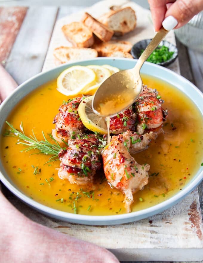 A spoon pouring some of the extra butter sauce right over the butter poached lobster