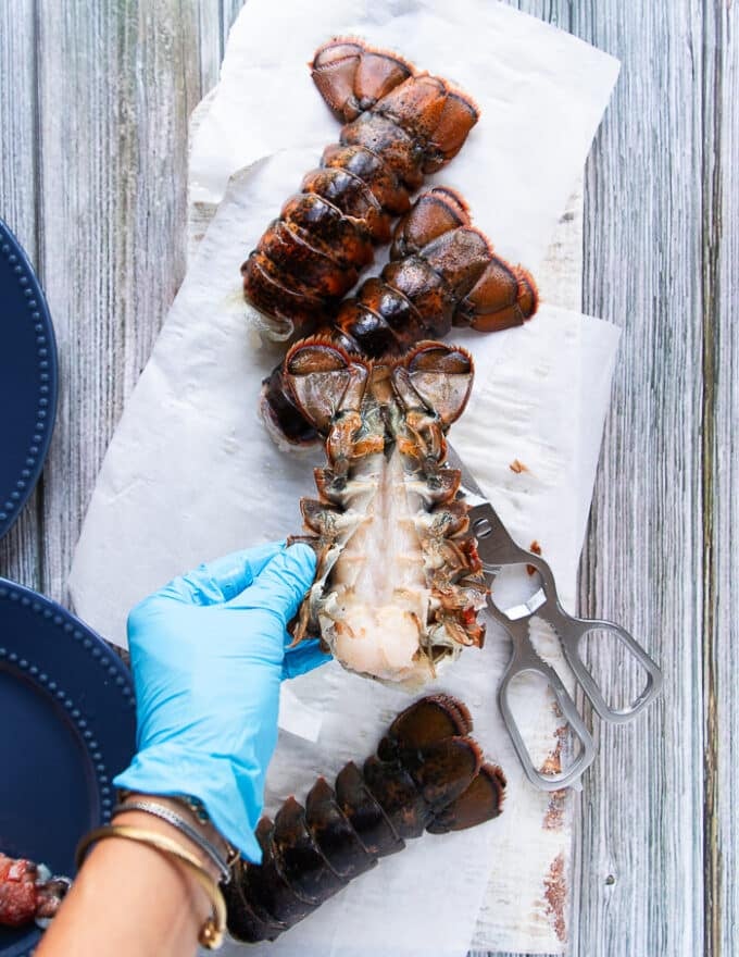 A hand trying to separate the meat from the shells inside the lobster tail