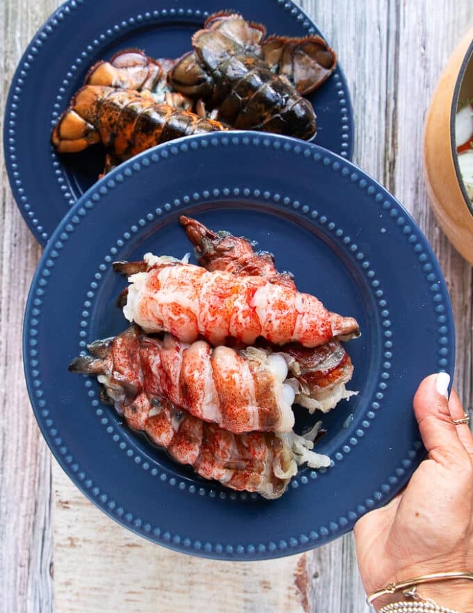 A hand holding a plate of lobster meat ready to butter poach