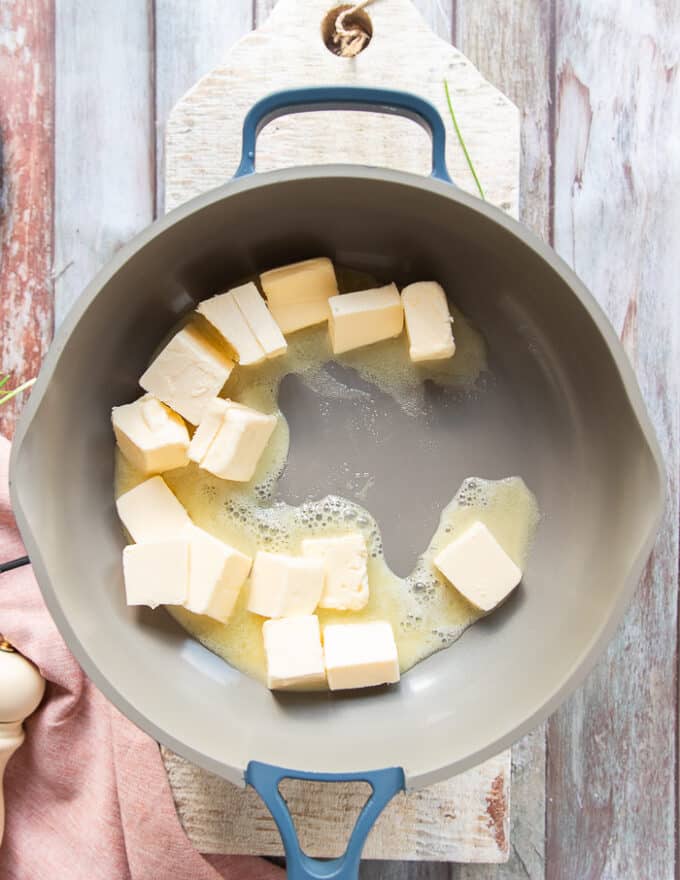 Butter cubes are added to a skillet and beginning to melt softly