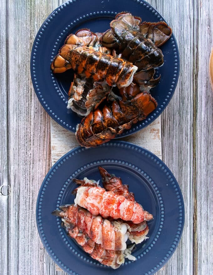 two separate plates on a wooden board, one with all the lobster meat and one with all the lobster shells. All separated to make lobster stock 