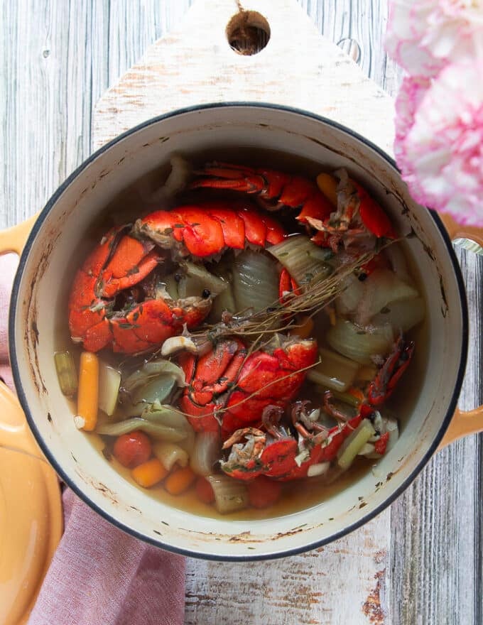 All the lobster shells, onions, garlic, bay leaves, carrots, celery, tomatoes, herbs, salt and pepper is added to a large pot and bubbling 