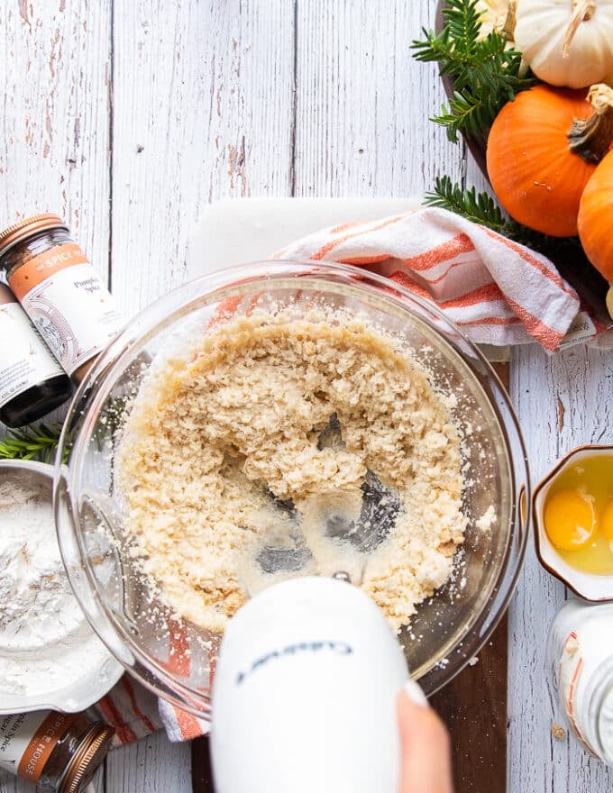 A hand mixer beating the butter, oil , light brown sugar and white sugar in a large bowl