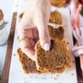 A hand holding a bitten piece of pumpkin bread recipe close up showing up the texture