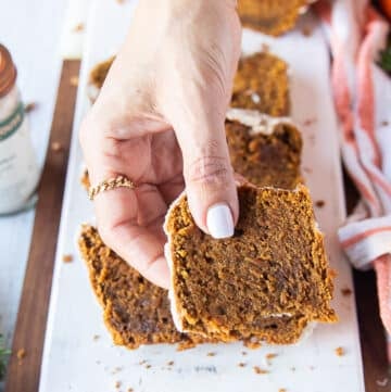 A hand holding a bitten piece of pumpkin bread recipe close up showing up the texture