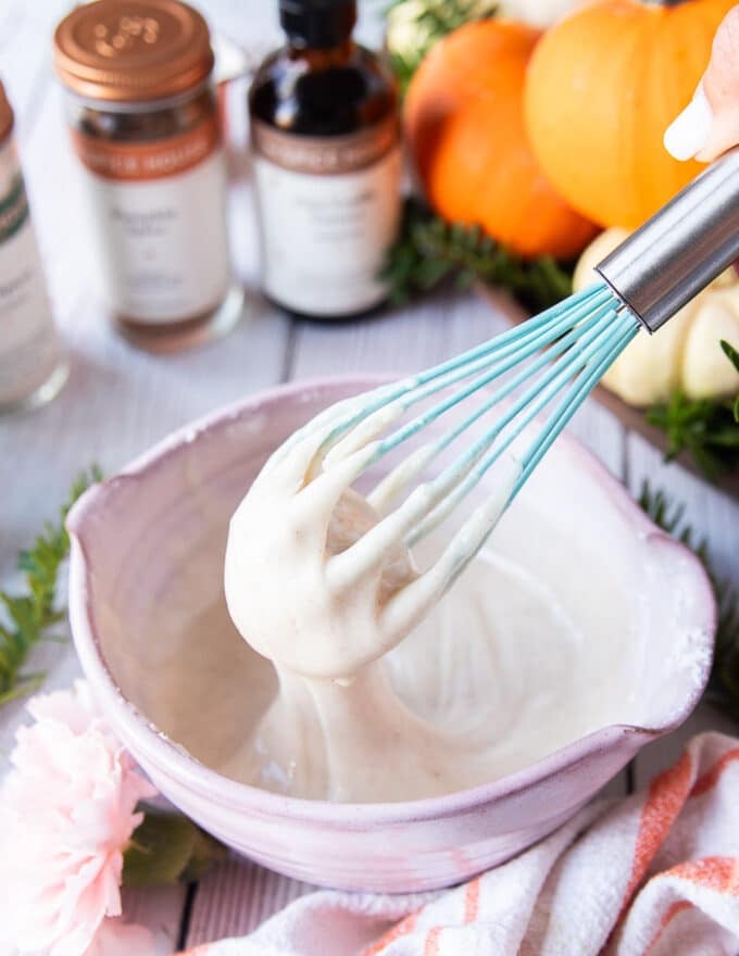 chai spice glaze ingredients all mixed in a bowl using a whisk and the whisk showing how thick it is