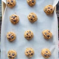 Scooped pumpkin oatmeal chocolate chip cookies on a baking sheet ready to bake
