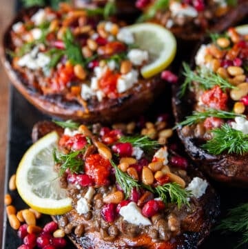 close up of one stuffed sweet potato showing the texture of the roasted sweet potatoes so soft and loaded with filling like lentils, pomegranates , hot sauce, fresh herbs, feta cheese