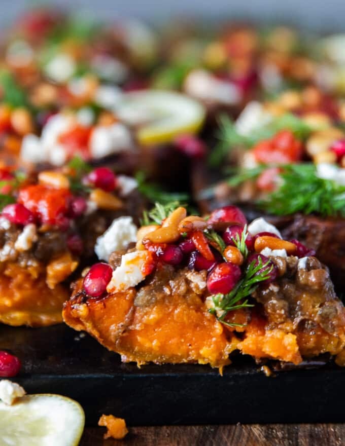 A stuffed sweet potato cut in half showing the creamy soft roasted sweet potatoes inside and the toppings on top.