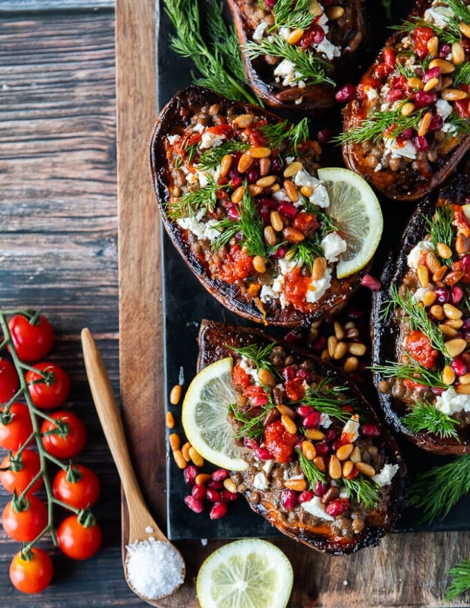 A full plate of stuffed sweet potatoes all garnished and stuffed ready to serve. The plate is garnished with dill, lemon slices and baby tomatoes.