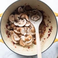 sliced cremini mushrooms are added to the pot of onions