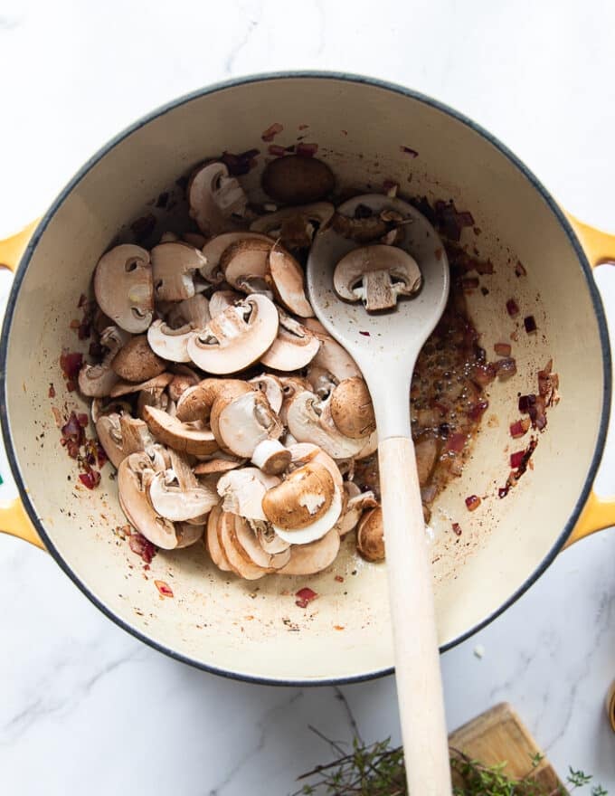 sliced cremini mushrooms are added to the pot of onions