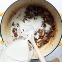 A hand pouring the milk and half n half into the pot