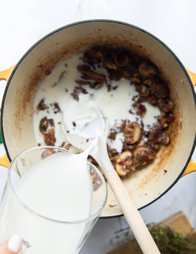 A hand pouring the milk and half n half into the pot 