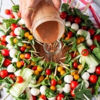 The simple balsamic olive oil dressing is poured into a small jar in the middle of the caprese wreath