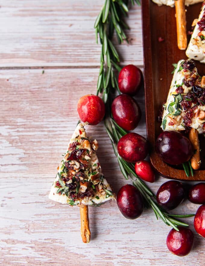 Close up of one cheese tree on a board with a sprig of rosemary and fresh cranberries