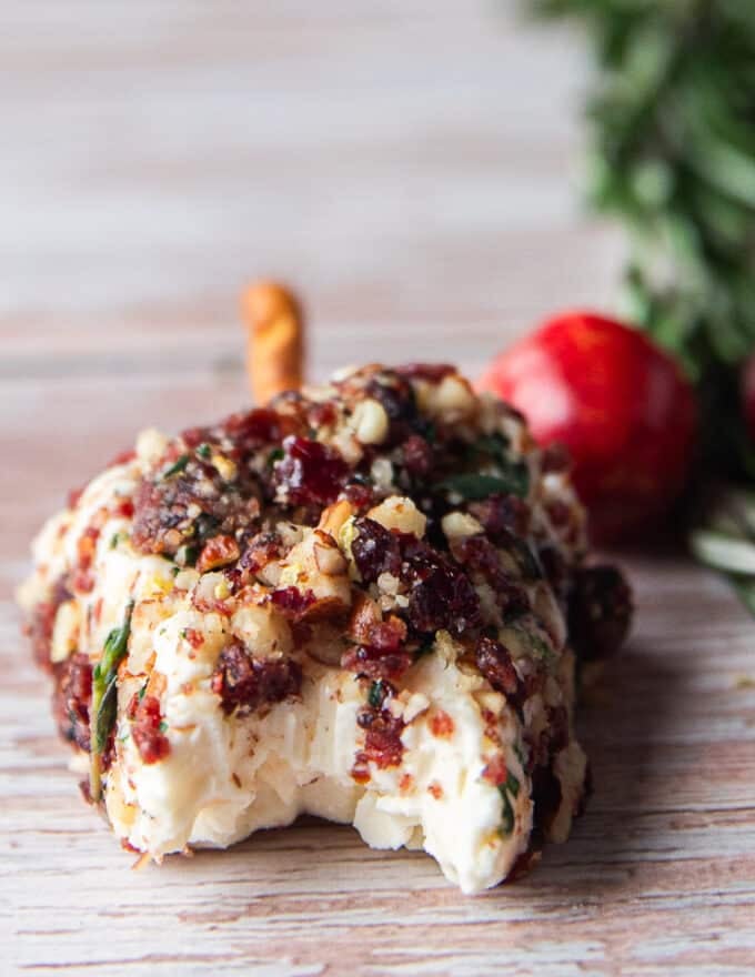 A bitten piece of cheese trees on a board showing the soft texture inside and the seasoning topping on top