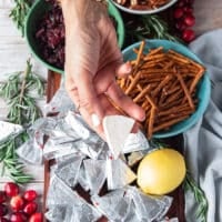 A hand holding a piece of wedge cheese that has been chilled so it holds it's shape well