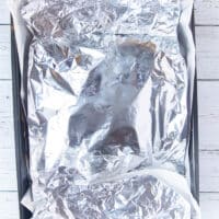 the lamb shoulder is covered in foil and ready to roast