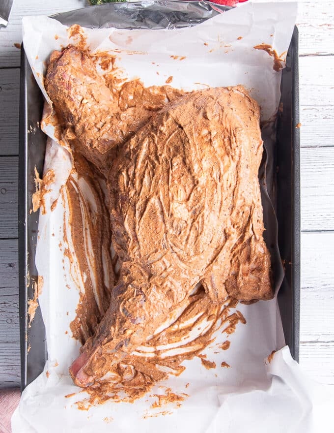 The whole shoulder of lamb slathered in the marinade 