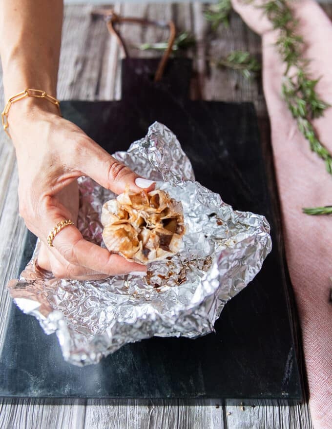 a roasted head of garlic just ready and unwrapped from the foil looking golden and super soft