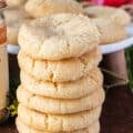 Long stack of 6 sugar cookies on top of each other showing the texture and specs of vanilla bean on a wooden board