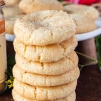 Long stack of 6 sugar cookies on top of each other showing the texture and specs of vanilla bean on a wooden board