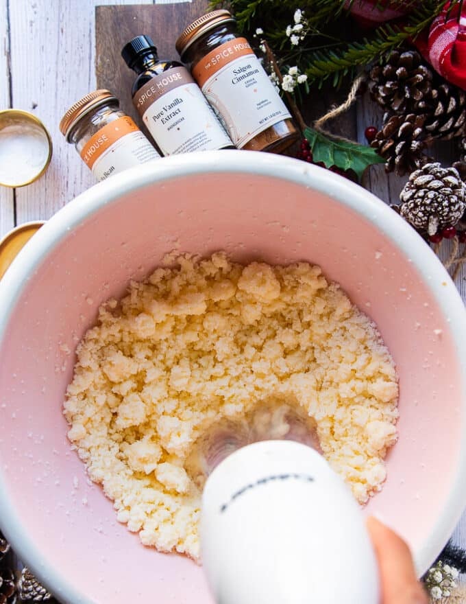 The mixer is blending the butter and sugar in a large bowl to make the sugar cookie dough