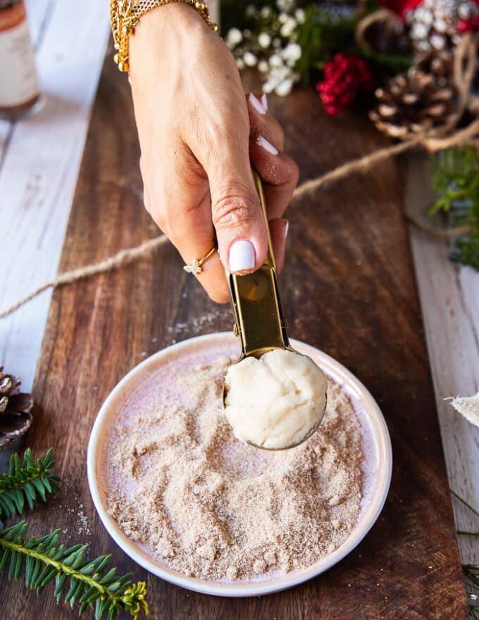 A hand scooping 1 inch size sugar cookie dough 