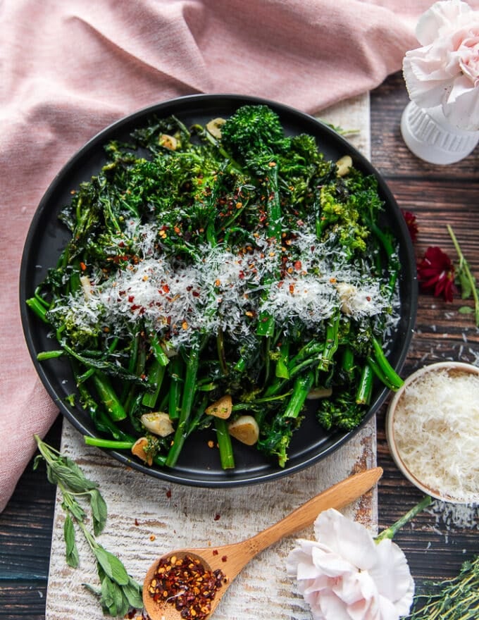 A plate of broccoli rabe perfectly sautéed and garnished with parmesan cheese and chilli flakes