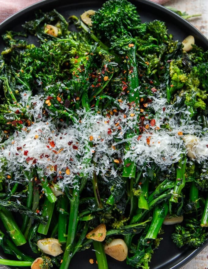 cropped macro shot of the cooked rapini on a plate with parmesan on top
