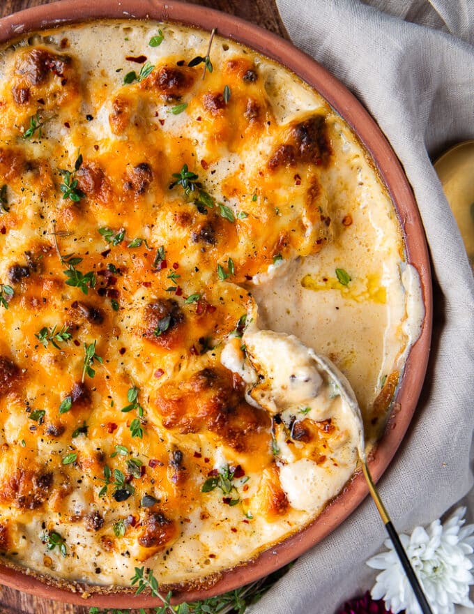 A serving spoon serving up the cauliflower casserole close up showing the saucy inside of the casserole close up