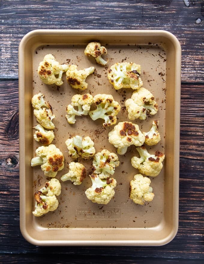 the cauliflower florets in a baking sheet, roasted and golden, ready to use 