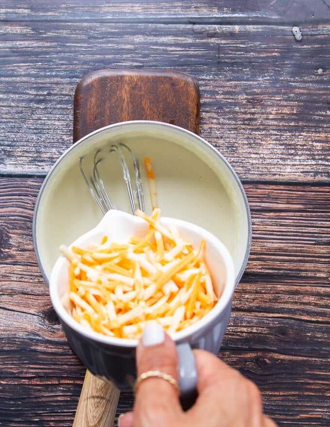 The cheese is being added into the pot to make the sauce cheesy