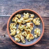 The roasted cauliflower is spread at the bottom of an oven safe casserole dish
